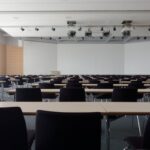 Spacious contemporary conference room with rows of tables and chairs, ready for meetings.