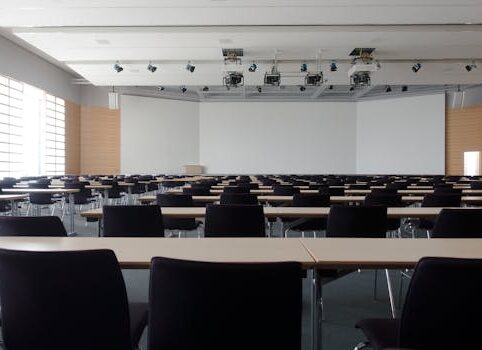 Spacious contemporary conference room with rows of tables and chairs, ready for meetings.